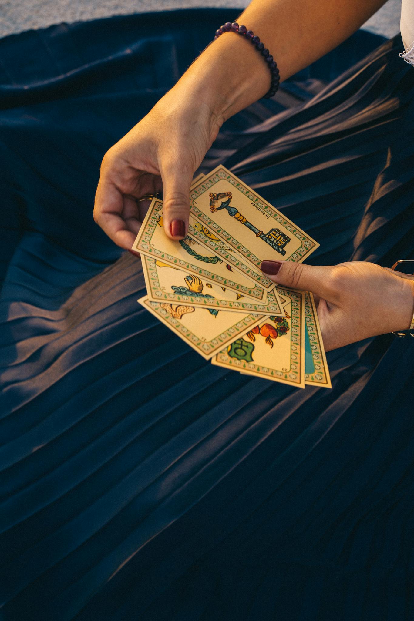 A woman holding tarot cards for a spiritual reading, set against a dark fabric backdrop.